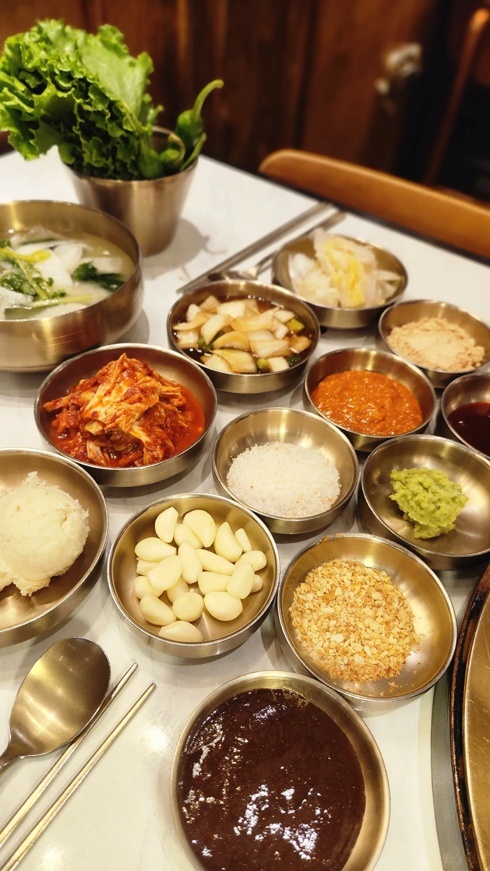 놋그릇에 나눠 담은 상차림 — 쌈장, 콩가루, 김치, 절임채소, 통마늘