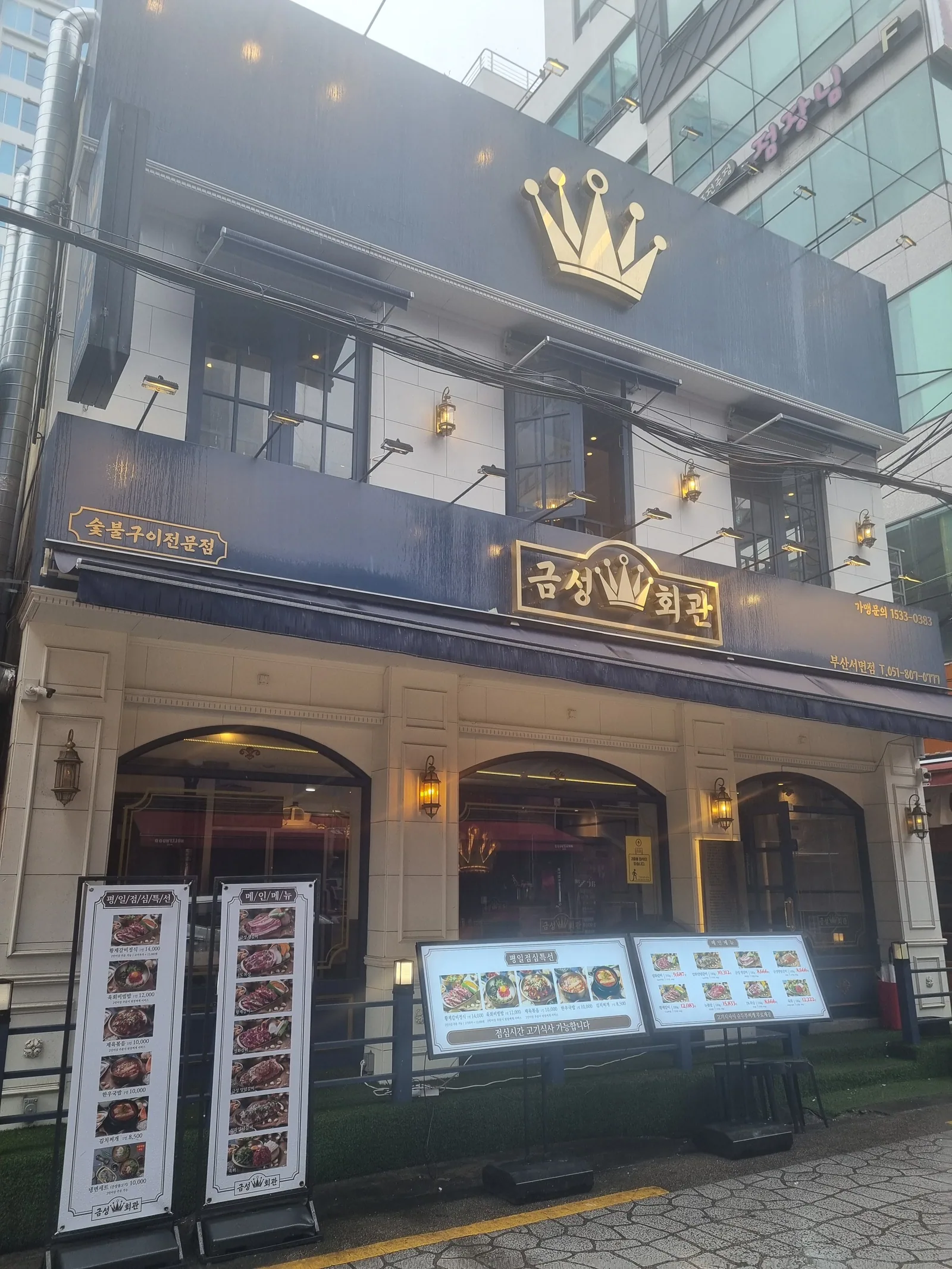금성회관 부산서면점 정면 — 아이보리 석고 파사드의 세 개 아치와 네이비 밴드 위 금색 왕관 조형, 금박 간판